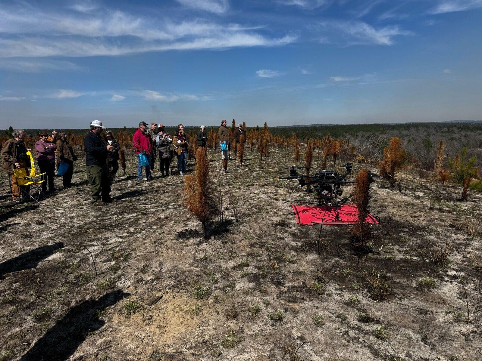 Drone demonstration area with attendees gathered around in a recently burned landscape